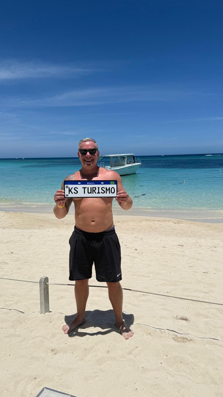 Kaká na praia de Roatán segurando uma placa da KS Turismo